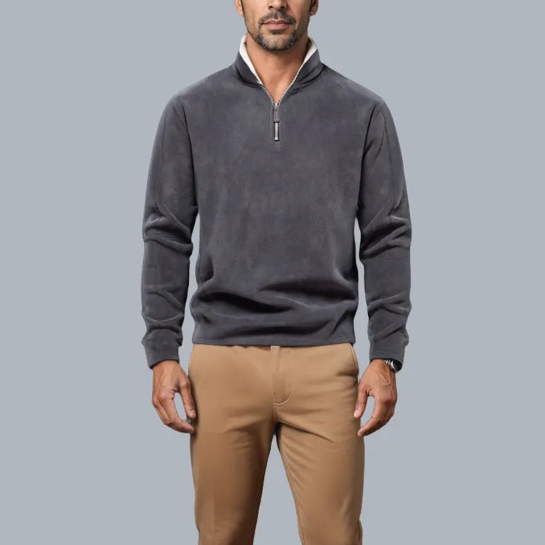 Man wearing a gray sweater and brown pants against a light gray background