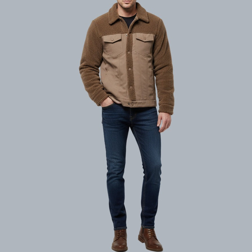 Man wearing a brown jacket and blue jeans on a gray background